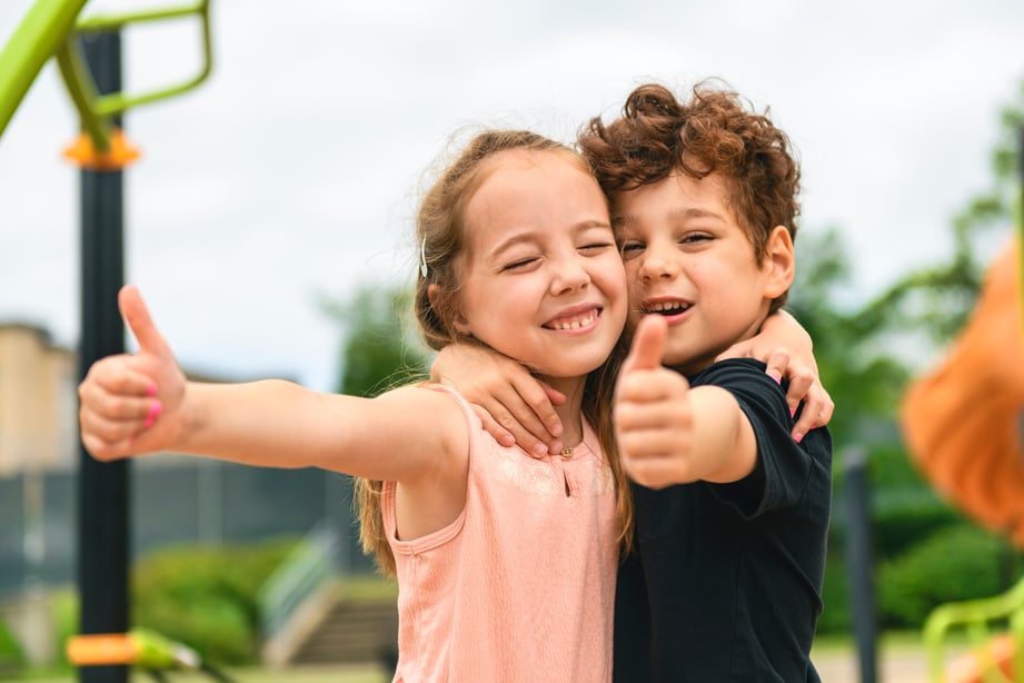 Boy and girl with arms around each other and flashing a thumbs up