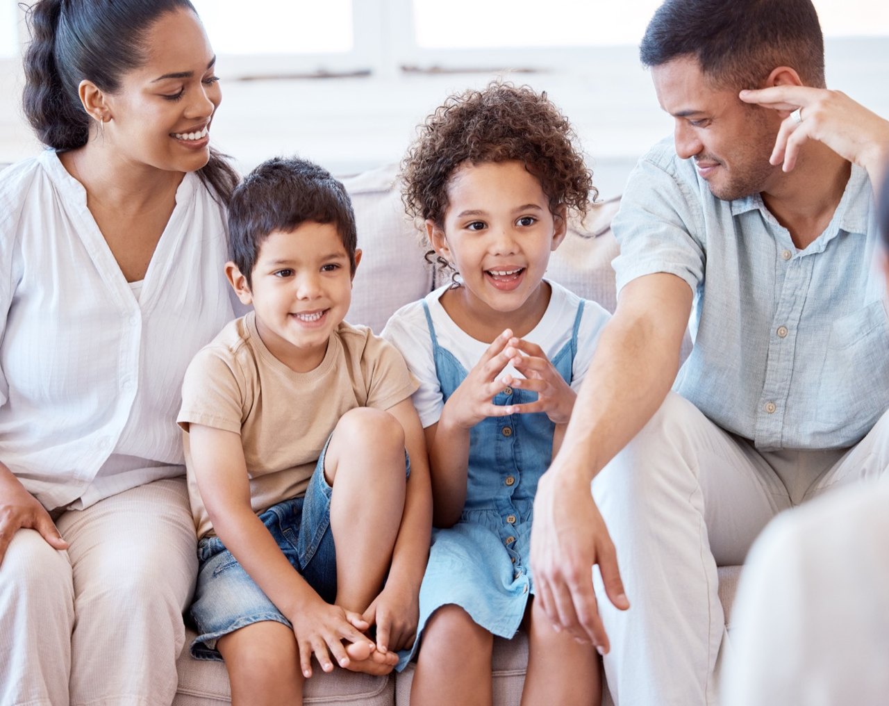 A family of four sitting together on a sofa and smiling